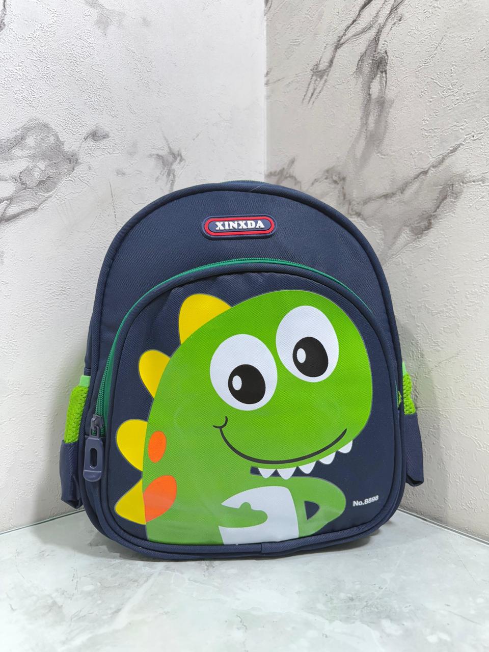 Divertido morral infantil con diseño de dinosaurio sonriente, ideal para los más pequeños . Sus colores llamativos y estilo tierno lo hacen perfecto para el jardín, colegio o paseos diarios